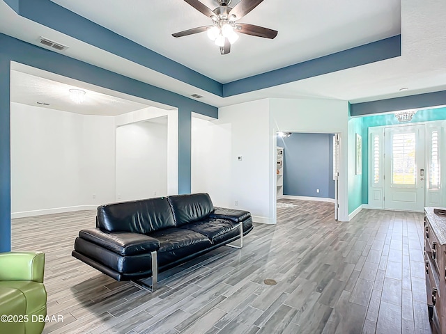 living room featuring a tray ceiling and ceiling fan