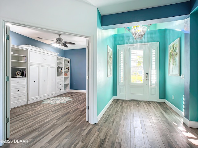 foyer entrance with hardwood / wood-style floors and ceiling fan with notable chandelier