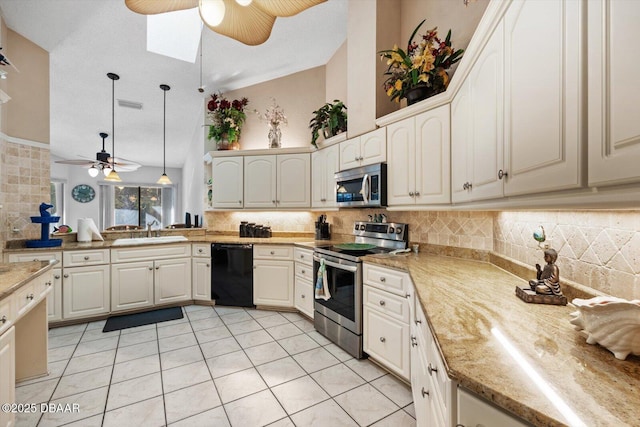 kitchen with a skylight, sink, hanging light fixtures, decorative backsplash, and appliances with stainless steel finishes