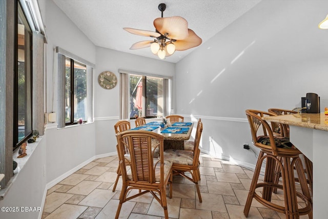 dining area with ceiling fan and a textured ceiling