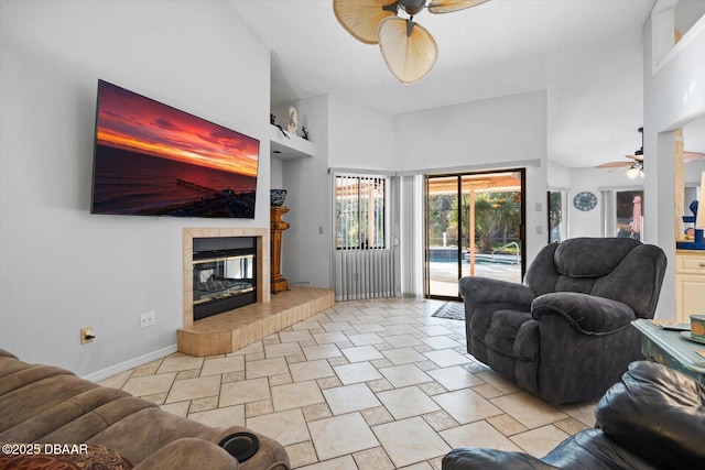 tiled living room featuring a tile fireplace, ceiling fan, and a high ceiling