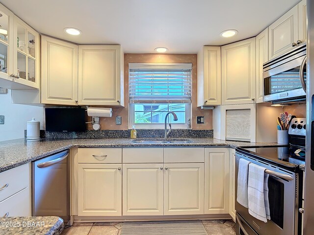 kitchen with glass insert cabinets, recessed lighting, stainless steel appliances, white cabinetry, and a sink