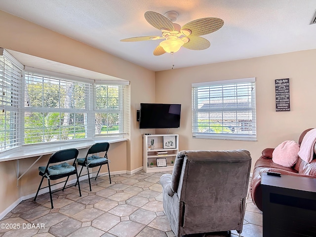 living area featuring a wealth of natural light, visible vents, baseboards, and a ceiling fan