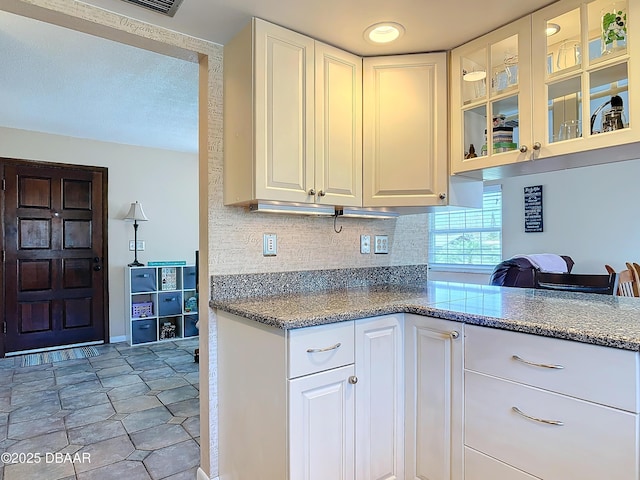 kitchen with glass insert cabinets, tasteful backsplash, light tile patterned flooring, and white cabinetry