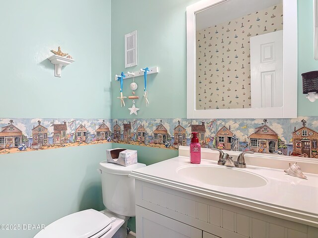 bathroom featuring visible vents, wallpapered walls, toilet, and vanity