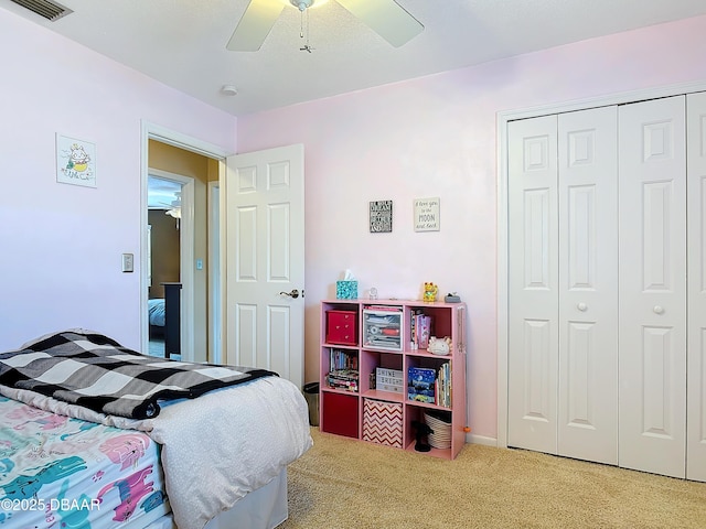 carpeted bedroom with a closet, visible vents, and ceiling fan