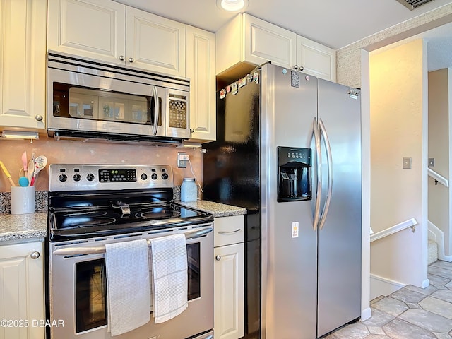 kitchen featuring light tile patterned floors, stainless steel appliances, and white cabinetry