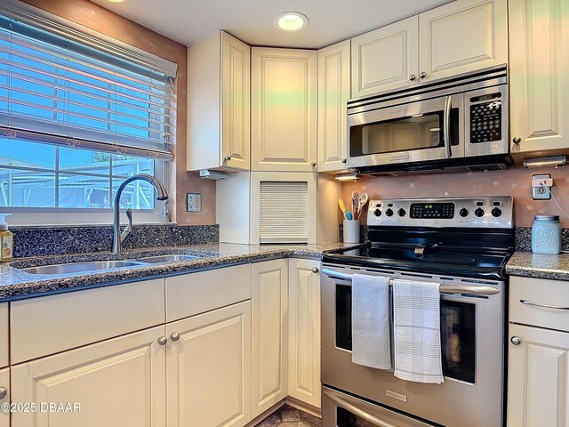 kitchen with a sink, dark stone countertops, recessed lighting, stainless steel appliances, and white cabinets