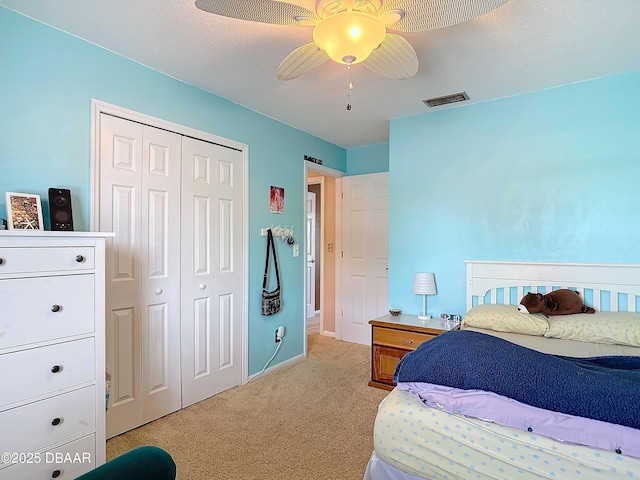 bedroom with visible vents, ceiling fan, light colored carpet, a barn door, and a closet