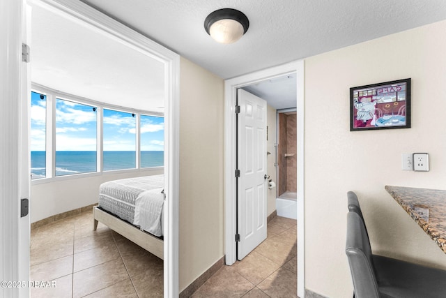 2625 S Atlantic Ave Unit 18Nw, Daytona Beach Shores, FL 32118 - bedroom with light tile patterned flooring, a water view, baseboards, and a textured ceiling