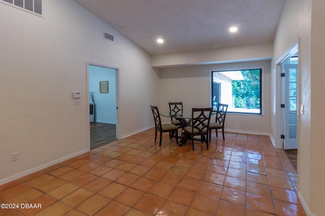 dining area with tile patterned flooring and high vaulted ceiling