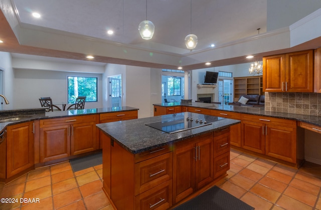 kitchen featuring black electric stovetop, sink, tasteful backsplash, decorative light fixtures, and a kitchen island