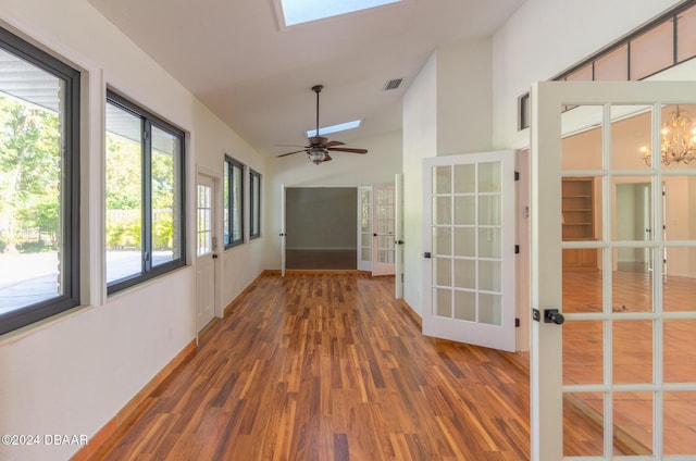 unfurnished sunroom with french doors, ceiling fan with notable chandelier, and vaulted ceiling with skylight