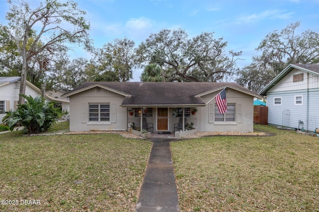 view of front facade with a shingled roof, fence, and a front yard