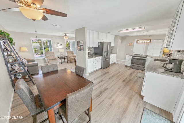 dining space with ceiling fan, sink, and light wood-type flooring