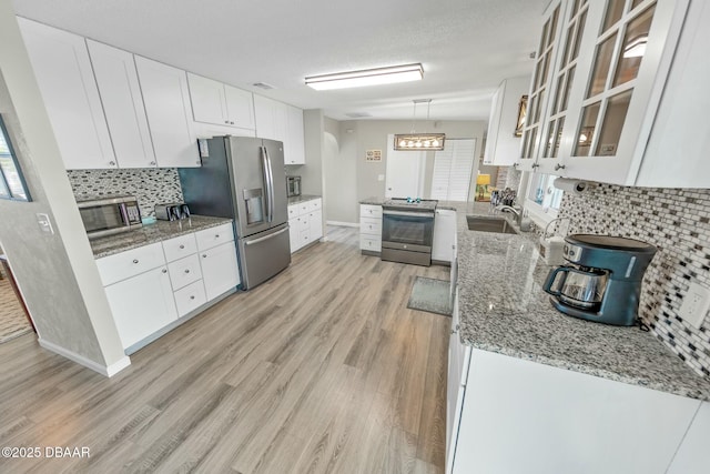 kitchen featuring sink, light stone counters, a textured ceiling, white cabinets, and appliances with stainless steel finishes