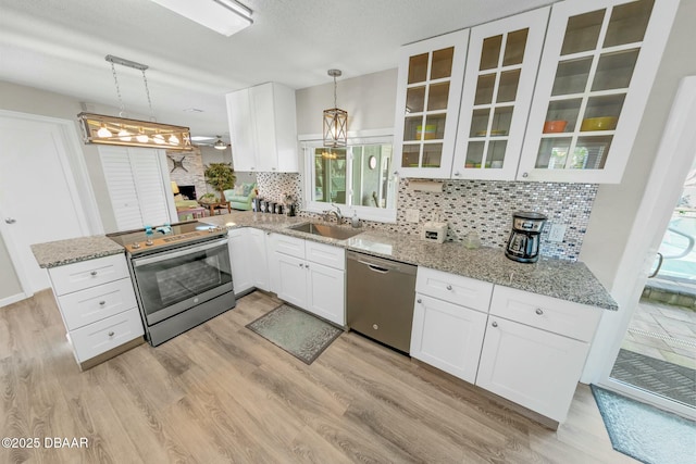 kitchen with tasteful backsplash, stainless steel appliances, sink, pendant lighting, and white cabinets