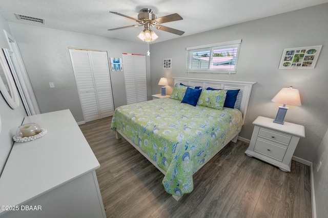 bedroom featuring dark hardwood / wood-style flooring, two closets, and ceiling fan