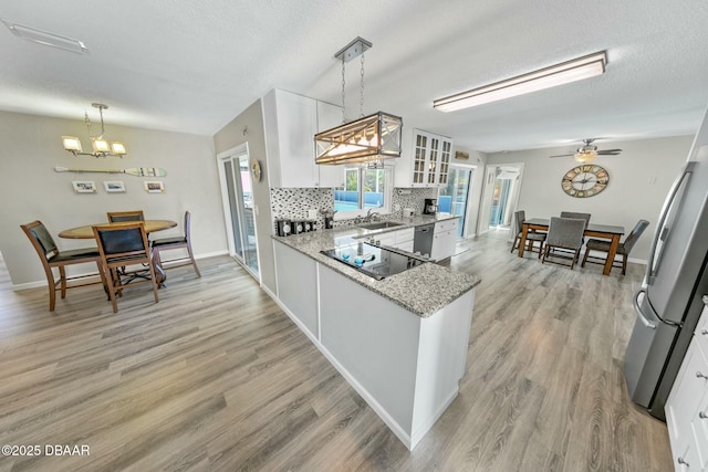 kitchen featuring light stone countertops, backsplash, sink, pendant lighting, and white cabinets