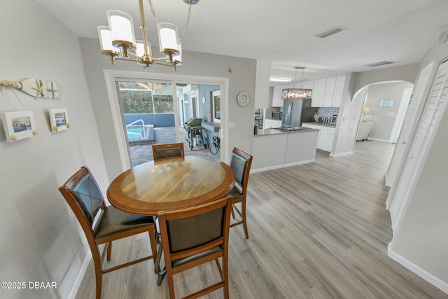 dining space featuring light hardwood / wood-style flooring and an inviting chandelier