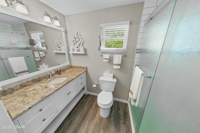 bathroom featuring vanity, hardwood / wood-style flooring, toilet, a textured ceiling, and a shower with shower door