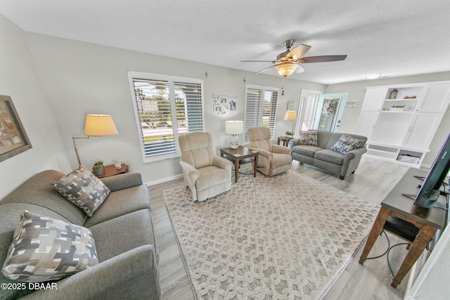 living room featuring ceiling fan, light hardwood / wood-style floors, and a textured ceiling