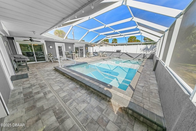 view of pool featuring a patio, glass enclosure, and ceiling fan