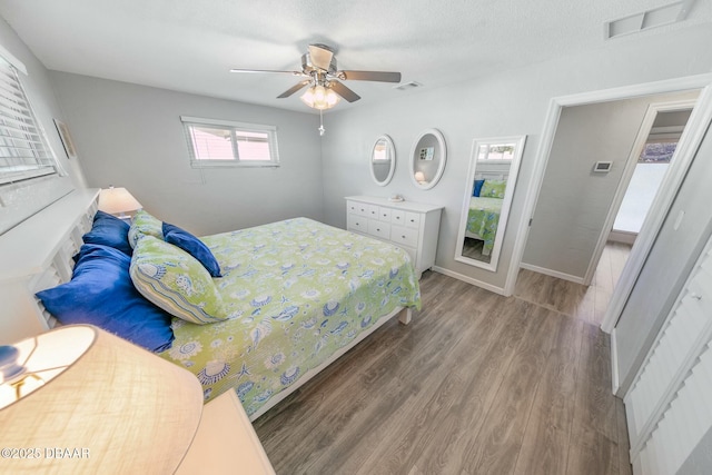 bedroom featuring ceiling fan, hardwood / wood-style floors, and a textured ceiling