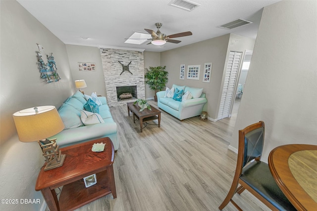 living room with ceiling fan, light hardwood / wood-style floors, and a fireplace