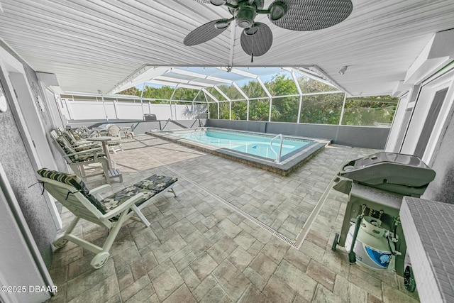 view of swimming pool with glass enclosure, a patio area, and ceiling fan