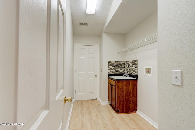 hallway featuring sink, a textured ceiling, and light hardwood / wood-style flooring