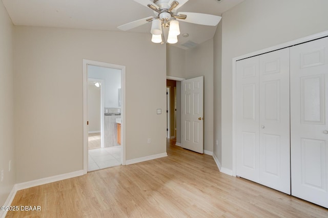 unfurnished bedroom featuring ceiling fan, light wood-type flooring, a closet, and vaulted ceiling