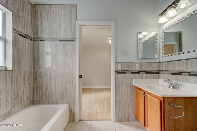 bathroom with ceiling fan, vanity, tile patterned flooring, tile walls, and a washtub