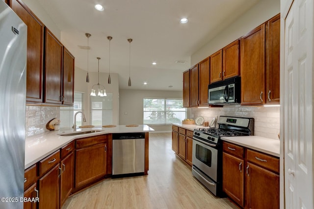 kitchen with decorative light fixtures, stainless steel appliances, sink, backsplash, and a chandelier