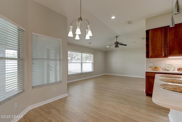 unfurnished dining area with lofted ceiling, light hardwood / wood-style floors, and ceiling fan with notable chandelier