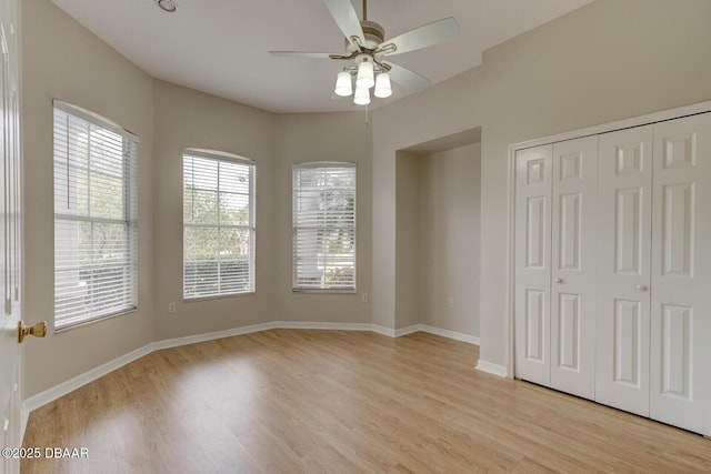 unfurnished bedroom featuring ceiling fan, light wood-type flooring, and a closet