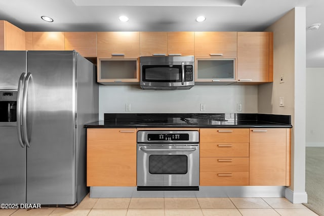 kitchen with dark stone counters, light brown cabinetry, light colored carpet, and stainless steel appliances