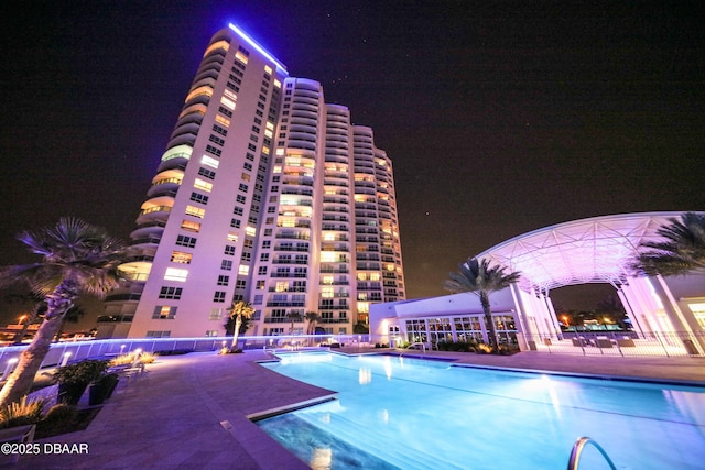 pool at night featuring a patio area