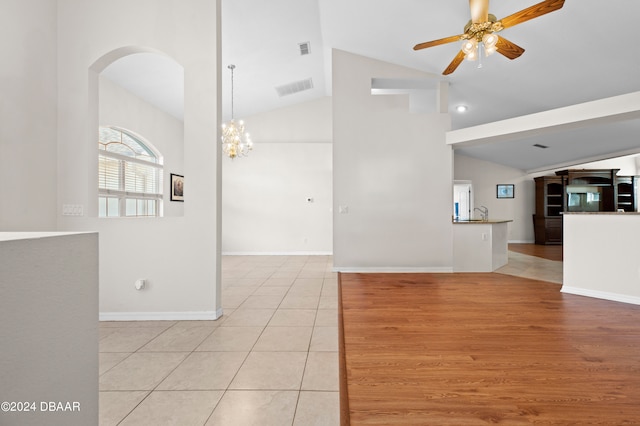 unfurnished room with high vaulted ceiling, light hardwood / wood-style floors, and ceiling fan with notable chandelier