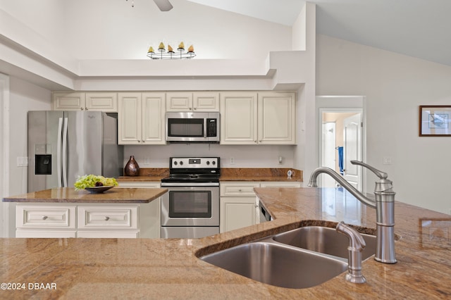 kitchen featuring light stone countertops, lofted ceiling, sink, and stainless steel appliances