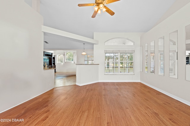 unfurnished living room featuring light wood-type flooring, lofted ceiling, and ceiling fan