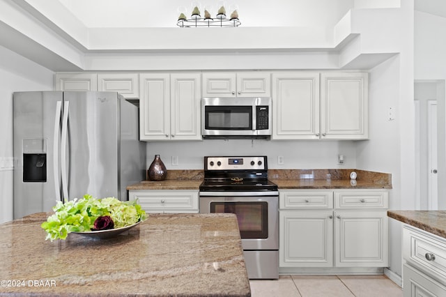 kitchen featuring stainless steel appliances, stone countertops, white cabinetry, and light tile patterned flooring