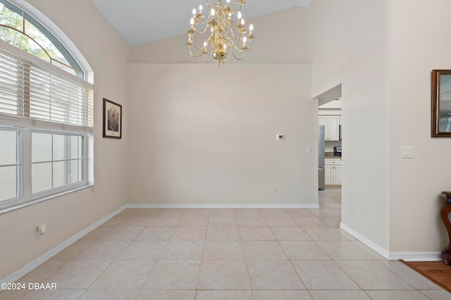 spare room featuring light tile patterned flooring, high vaulted ceiling, and a notable chandelier