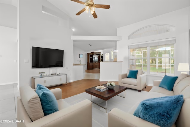 living room with light hardwood / wood-style floors, ceiling fan, sink, and high vaulted ceiling