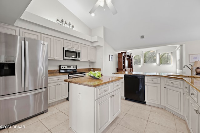 kitchen featuring a center island, vaulted ceiling, kitchen peninsula, sink, and appliances with stainless steel finishes