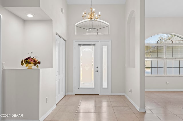 tiled entrance foyer featuring a towering ceiling and a notable chandelier