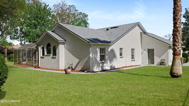 rear view of property featuring glass enclosure and a yard