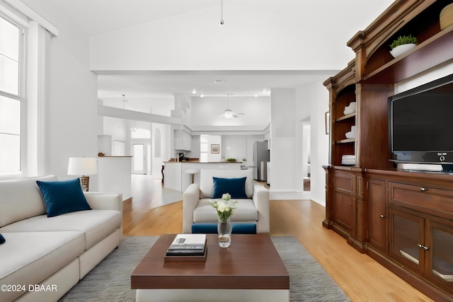 living room with light wood-type flooring, lofted ceiling, and ceiling fan