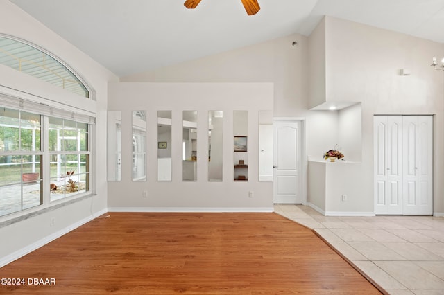 spare room with light hardwood / wood-style floors, ceiling fan, and high vaulted ceiling