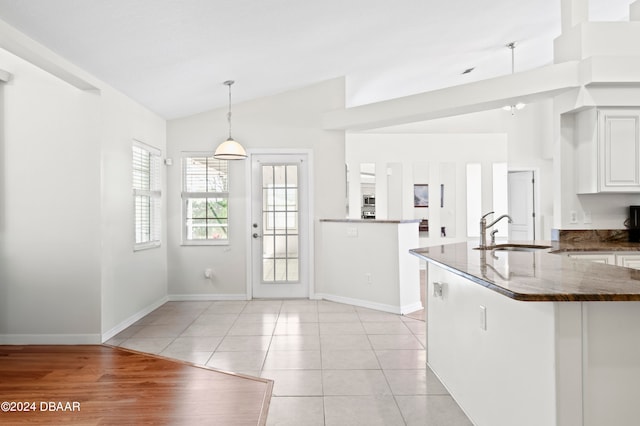 kitchen with white cabinetry, sink, pendant lighting, and vaulted ceiling